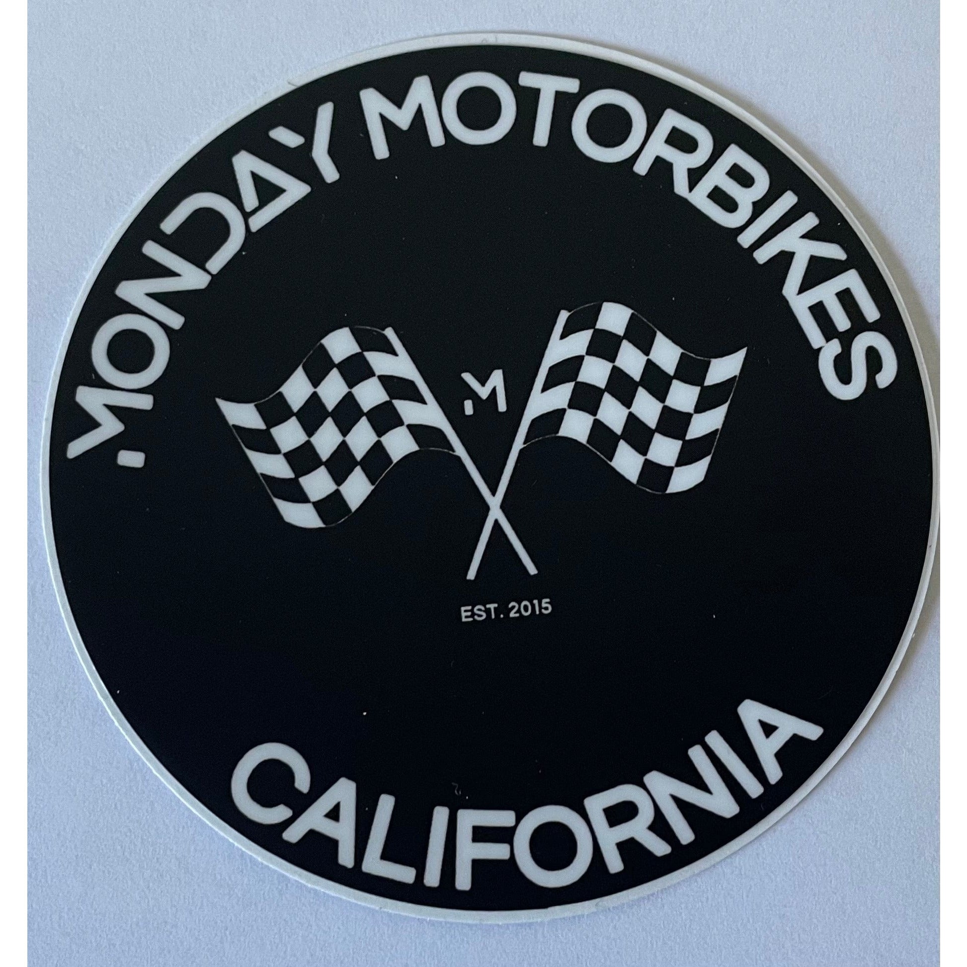 A circular sticker with a checkered flag design, representing speed and performance.