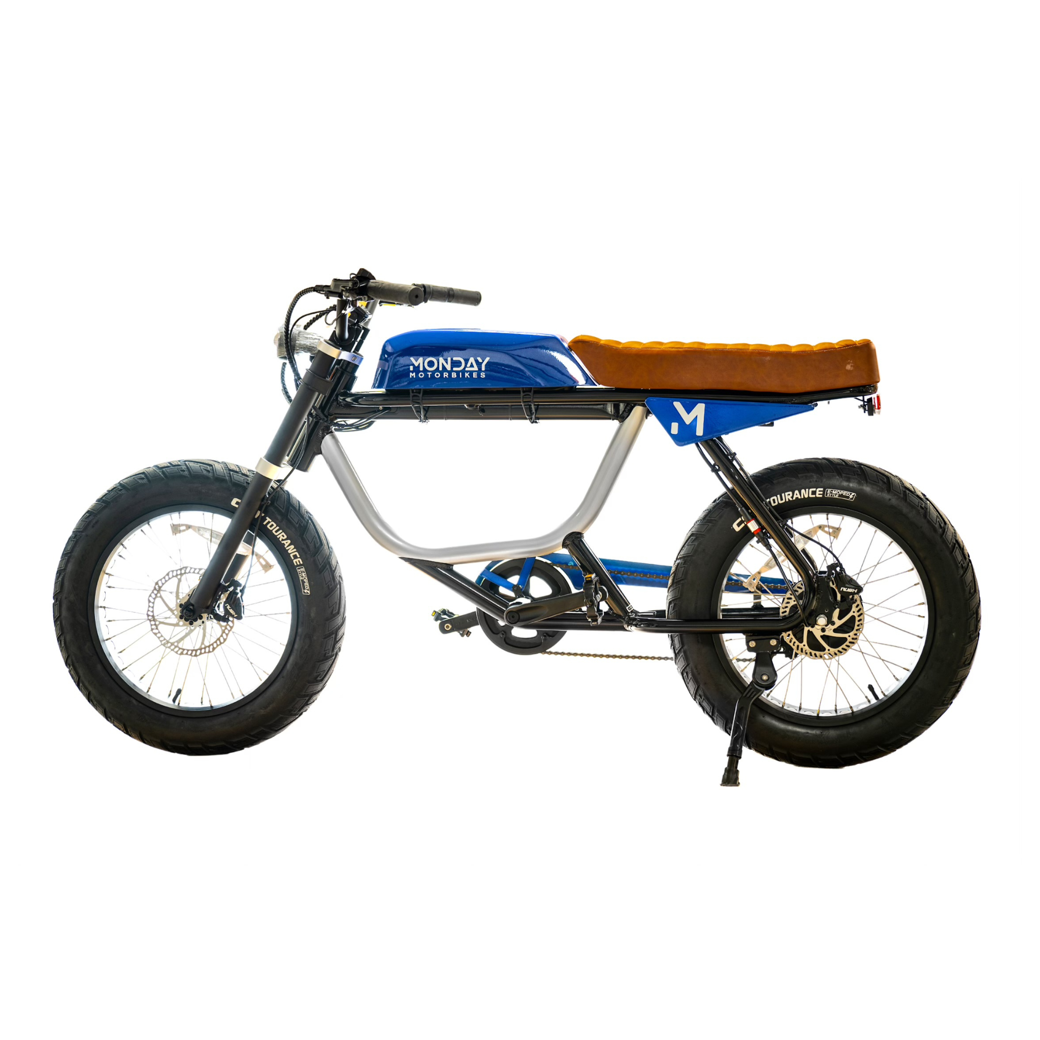 ANZA 1,000W electric motorbike in cafe racer style with silver frame, blue tank panel, and tan leather seat. Features fat tires, disc brakes, and sleek retro design with modern elements. Side view showcasing the distinctive Monday Motorbikes branding and minimalist profile.